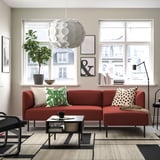 Vibrant red LILLEHEM sofa with green/white pillows, rug, pendant light, sleek coffee table, plant, bowl, wall art.