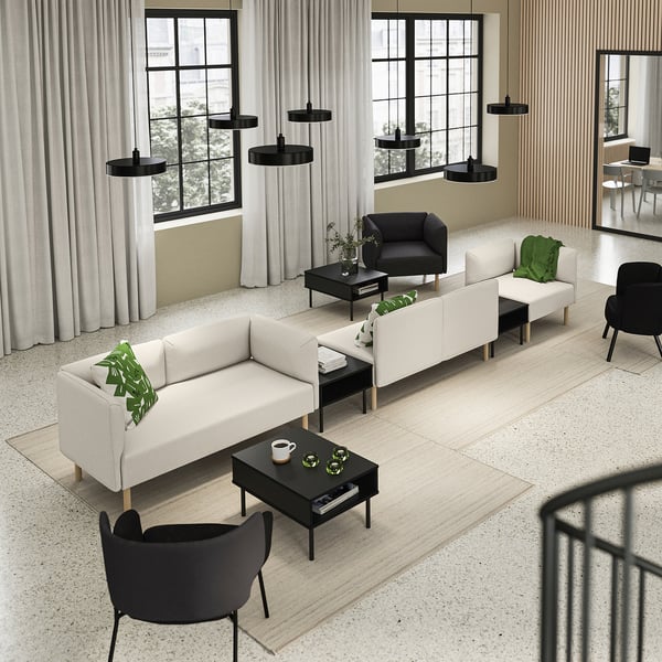 Modern living room with a white LILLEHEM modular sofa, black chair, wooden coffee tables, hanging lamps, and large windows with curtains.
