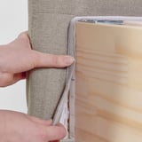Person holding a fabric cover designed for a storage divan bed, showcasing its ability to be easily removed for washing.