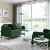 Bright living room with large windows, green couch and chair, white tables, gray rug, black and white art, and sheers.