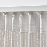 White curtains with dots hang from silver hooks, filtering light and offering privacy.
