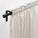 Curtain rod with beige & white polka dot curtains hanging, featuring a black l-bracket and gliders for smooth operation.