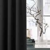 Modern room decor: MAJGULL blackout curtains frame a window with a textured vase holding dried branches and stacks of books.