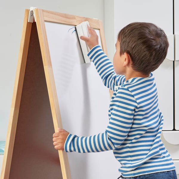 A child using MÅLA whiteboard pens, drawing on an easel.