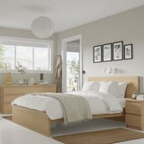 Minimalist bedroom with white bed, wooden drawers. Clean, modern design.