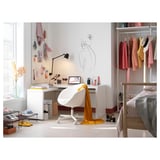 Modern home office with white MALM desk, white chair, pink decorations, laptop, lamp, and clothes rack.