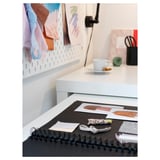 This image shows a white MALM desk with a pull-out work surface and a spiral-bound notebook on top.