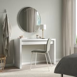 Modern bedroom with MALM dressing table, mirror, chair, and lamp. Curtained window, grey bedspread.