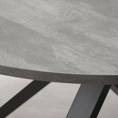 Close-up of modern table edge. Grey tabletop with smooth, beveled edge supported by angled metal legs.