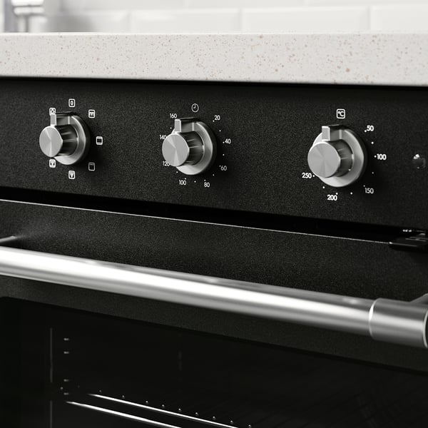 Black oven control panel with three dials for temperature and settings, indicating modern convenience and traditional cooking functionality.
