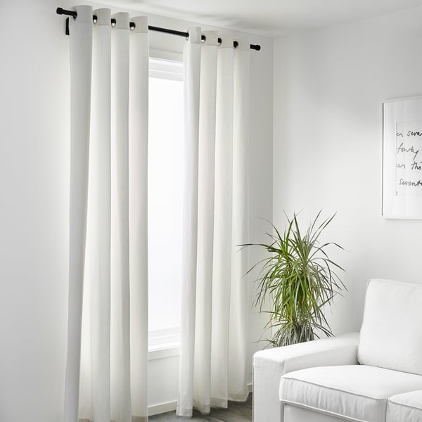 Minimalist room with MERETE light-blocking curtains on black rod, plant, and chair.