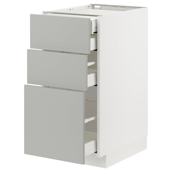 Depicts a white METOD kitchen cabinet with three grey drawers partially open.