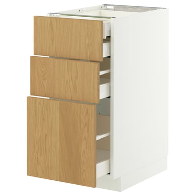 A white METOD kitchen cabinet with three wooden drawers. The drawers have a light oak finish and are partially open, revealing their interiors.