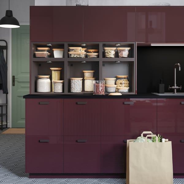Kitchen with maroon MITTLED cabinets, glass jars with food items, and paper bag on floor.