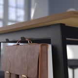 Brown leather bag hooked on black shelf, showing bag storage.