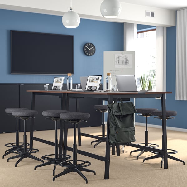 Modern office with blue walls, high table, & black stools with gray cushions.
