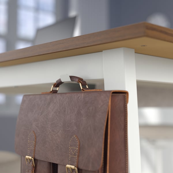 Brown leather bag hangs on metal hook under wooden ledge.