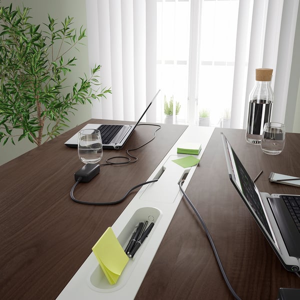 Conference table with built-in cable management, pen holders, and footrests for comfort, suitable for meetings and work.