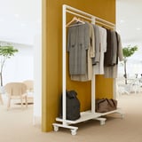 MITTZON coat rack with clothes and bags, mustard wall, wooden chairs.