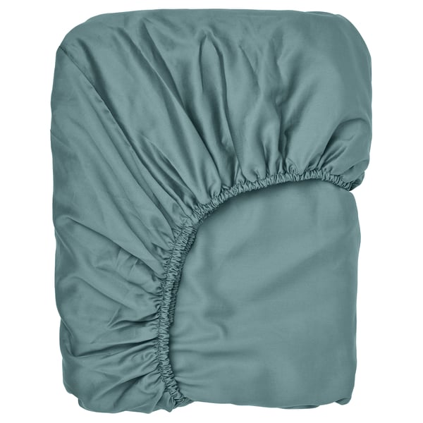 A neatly folded greenish-blue fitted sheet with gathered edges, made from cotton and lyocell, ready for use on a bed up to 26 cm thick.