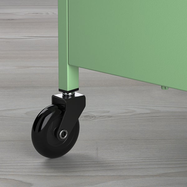 Close-up view of green metal trolley wheel on wooden floor.