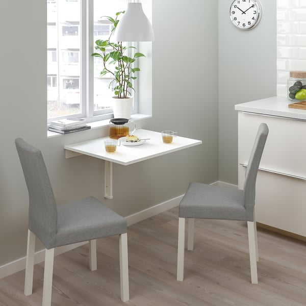 Small kitchen nook with white foldable table and gray chairs; minimalist design.