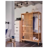 Scandinavian-style room with wooden wardrobe, white drawers, and bed, accessories displayed