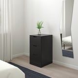 Black NORDLI 3-drawer chest, plant, mirror, bed, rug.