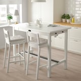 White bar stool with curved back, cushioned seat, and solid wood frame next to matching table in kitchen.