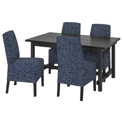 Black metal dining table with four blue floral chairs.