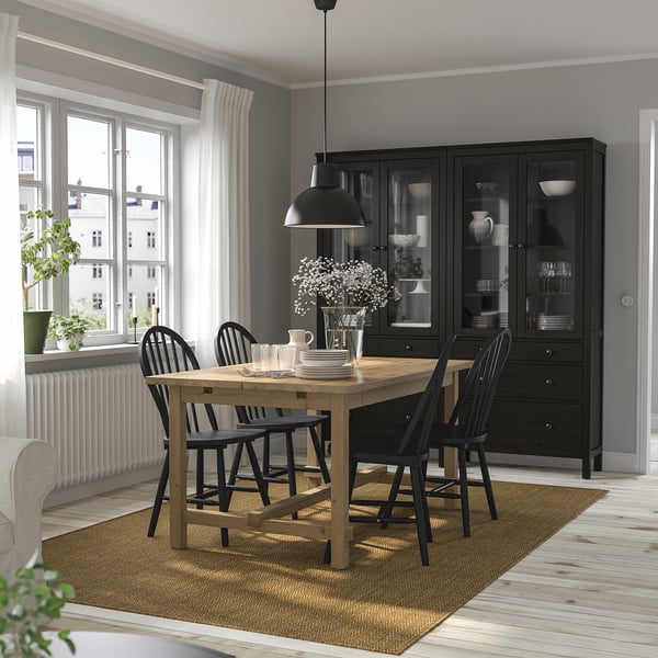 Modern dining setup with NORDVIKEN extendable table, 4 black chairs, black cabinet, beige rug, in bright, airy room.