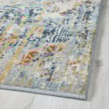 Rug with faded, intricate patterns in blues, greens, and mustards, laid on light wood floor, showcasing quality and texture.