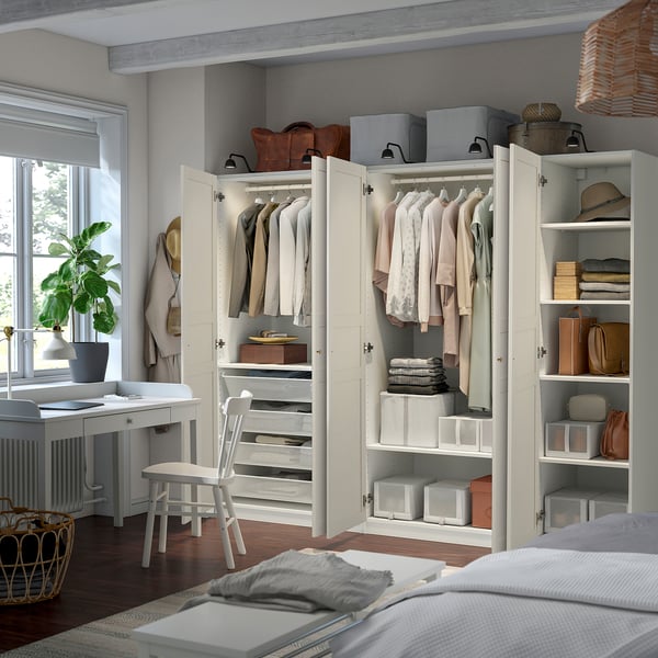 Modern bedroom with lit PAX wardrobe, organised clothes, desk, and large window.