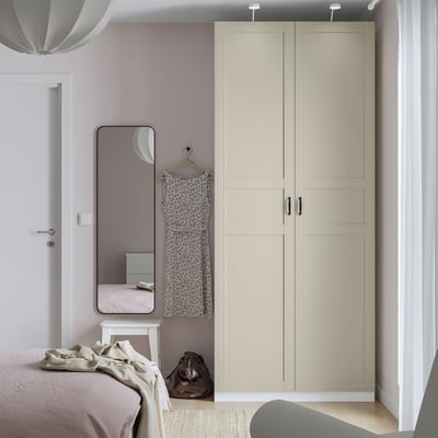 Modern bedroom with IKEA PAX wardrobe, mirror, and pink-beige bed.