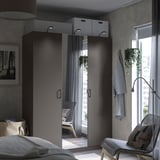 Modern bedroom with large mirrored PAX wardrobe reflecting a chair, featuring sleek handles and integrated lighting.