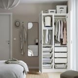 Neat bedroom with open wardrobe showing organized clothes, drawers, and mesh baskets. Hangers and boxes keep items tidy and visible.