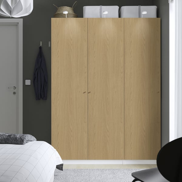 The is: modern bedroom featuring a large wooden PAX wardrobe, matching grey decor, and minimalist furniture.