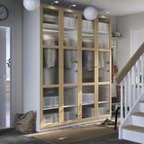 Wooden PAX wardrobe with frosted glass in gray room. Near stairs, with rug and decor.