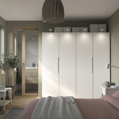 Modern bedroom with PAX wardrobe, led lights, black lamp, side table, and cozy bed.