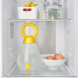 A fridge containing a water dispenser jar with a tap, fruit, and vegetables.