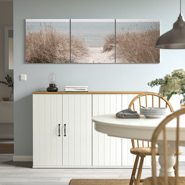 Triptych beach scene art above sideboard, adds depth to minimalist decor.