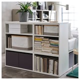 A white PLATSA bookshelf, holding books and a plant.