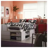 Neat bedroom with white PLATSA bed, black-and-white bedding, red side table, pink walls.