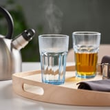 Tray with two glasses: one steaming, one filled with tea, next to kettle.