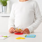 An a child arranging colorful beads on a red plastic base, learning fine motor skills while creating art.