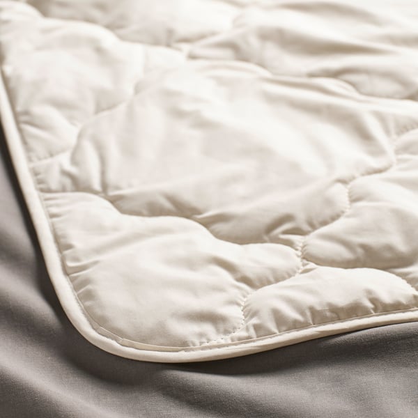 Close-up of a soft, cream-colored duvet, showcasing its smooth, high-quality fabric and neat stitching.