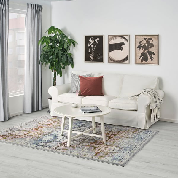 Stylish living room with RANDBÖL rug, sofa, coffee table, plant, and three art pieces.