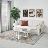Stylish living room with RANDBÖL rug, sofa, coffee table, plant, and three art pieces.