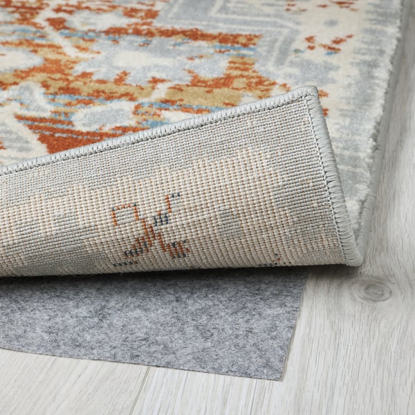 Multicolored rug with rolled edge on wooden floor.
