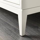 Close-up of white, sleek cabinet leg; fine craftsmanship.